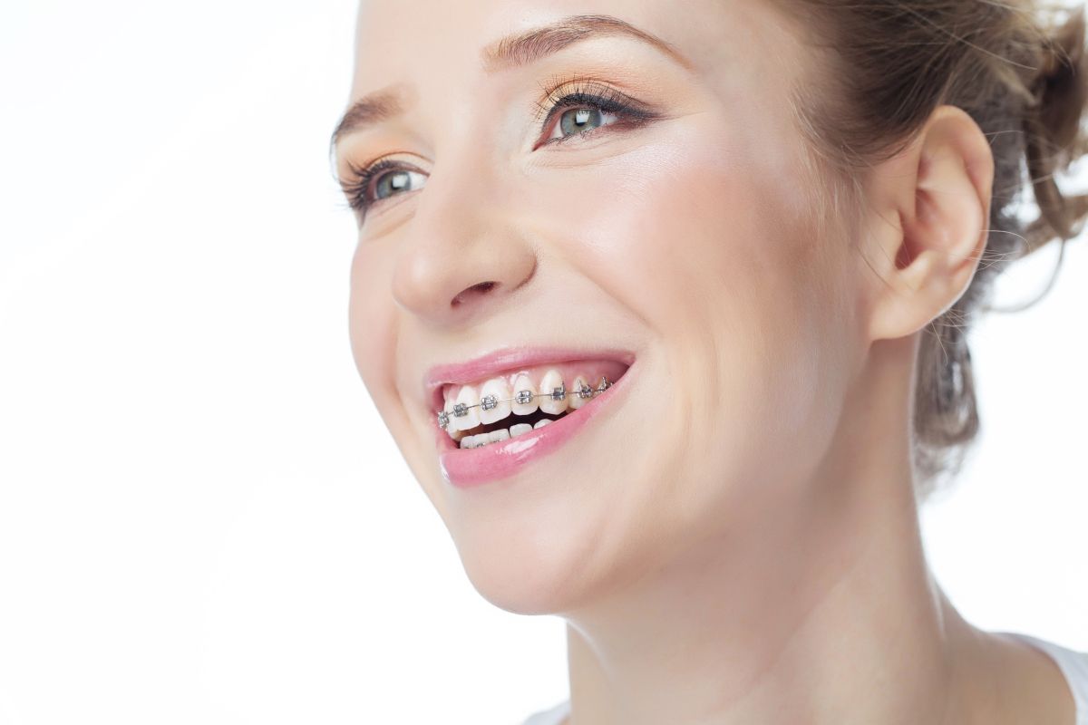 Woman smiling brightly, showcasing healthy white teeth against white background.