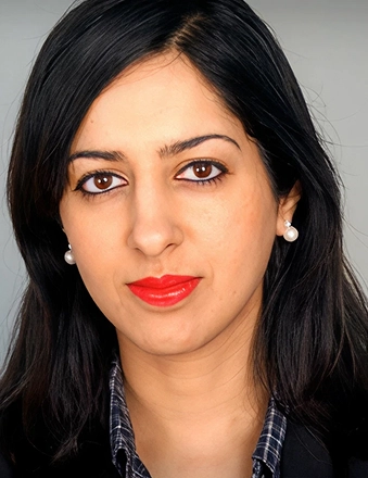 Professional headshot of woman with dark hair and red lipstick against neutral background.