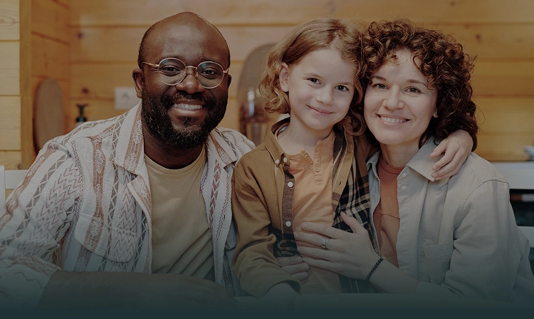 Three smiling people posing together indoors in a warm, welcoming dental office setting.