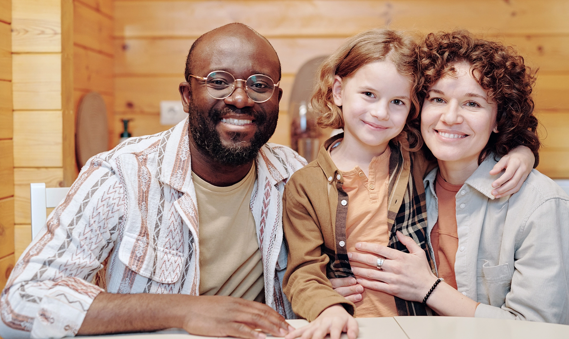 Three smiling dental professionals posing together at a clinic desk, representing friendly team care.