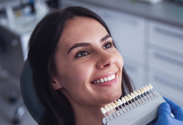 Smiling woman holding orthodontic model in modern dental office setting.