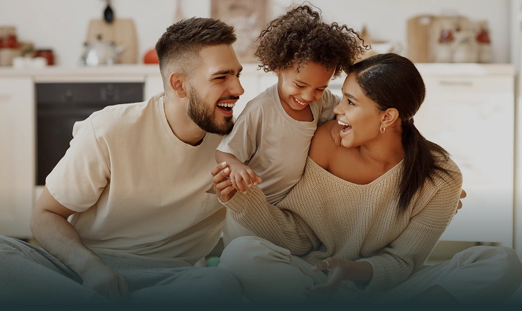 Happy family of three smiling together on couch at home