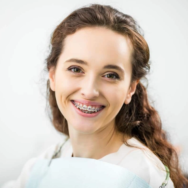 Young woman smiling at camera wearing white shirt in professional dental office portrait.