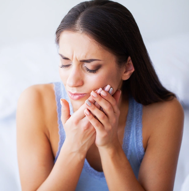 Woman holding face in pain, expressing dental discomfort or toothache concern.