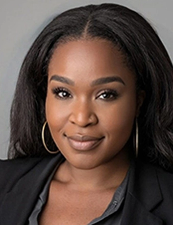 Professional headshot of a woman in black blazer against gray background for dental practice.