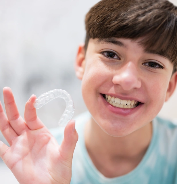 Young boy smiling at camera with hands covered in soap bubbles, promoting dental hygiene and oral care.