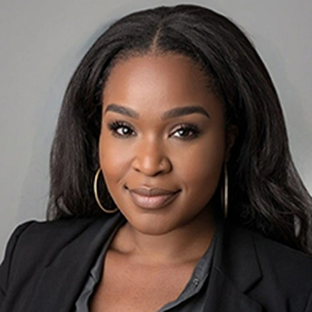 Professional headshot of a woman in black blazer against gray background for dental practice.