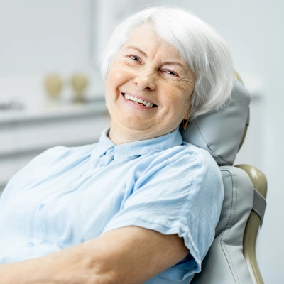 Senior woman smiling in dental chair during examination at dental office.