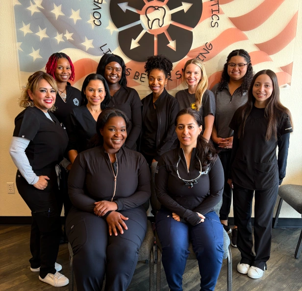 Team of dental professionals in black uniforms posing together in front of American flag backdrop.