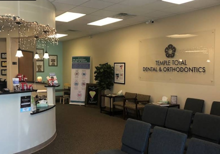 Dental office reception area with waiting chairs, front desk, and professional décor displaying practice branding.